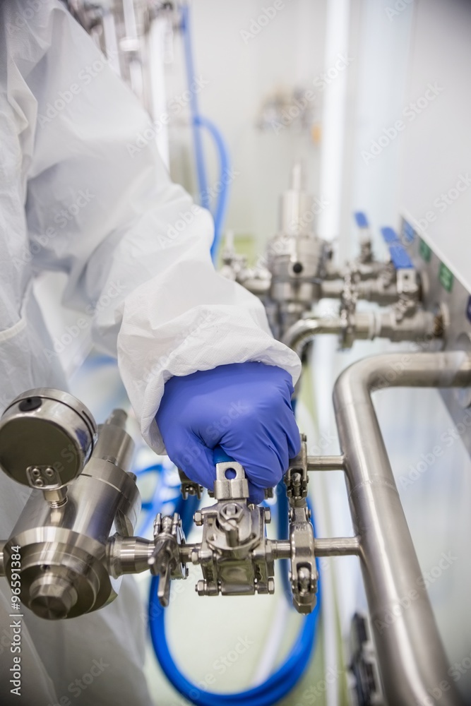 Scientist working with large vat and tap Scientist working with large vat and tap