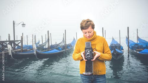 Beautiful young woman photographing gondolas in Venice, Italy