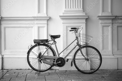 B&W vintage bicycle parked next to a white wall.