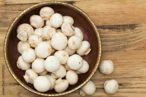 mushrooms in bowl on brown wooden background