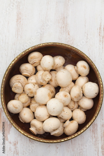 mushrooms in bowl on white wooden background