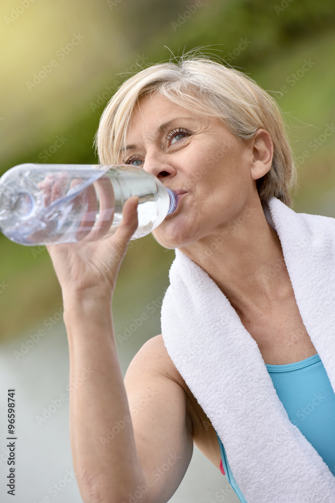 Senior woman drinking water after exercising Senior woman drinking water after exercising