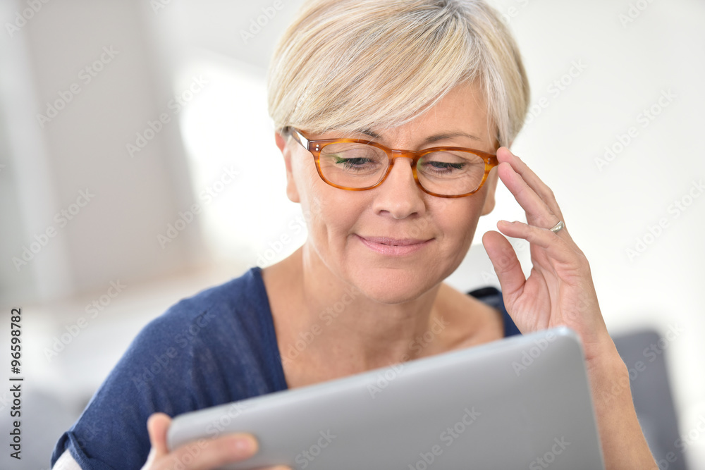 Senior woman with eyeglasses browsing on digital tablet Senior woman with eyeglasses browsing on digital tablet