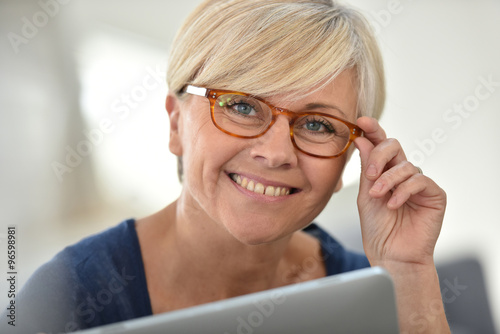 Senior woman with eyeglasses browsing on digital tablet