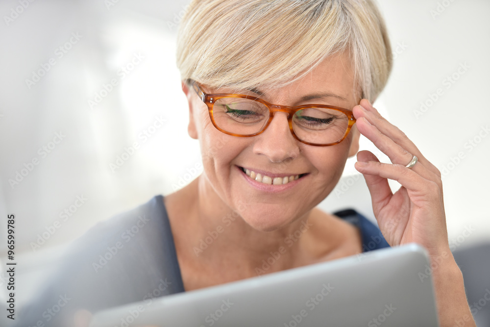Senior woman with eyeglasses browsing on digital tablet