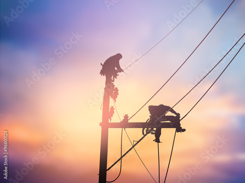 Silhouette electrical workers are installing high voltage system