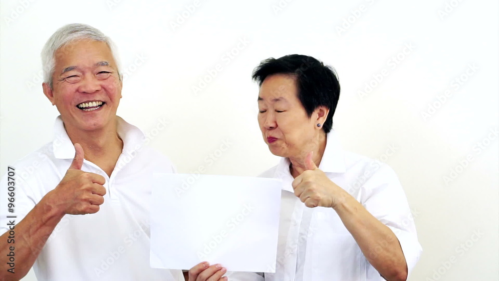 Asian senior couple look at the white sign together. Surprise and happy with the deal on blank white sign Asian senior couple look at the white sign together. Surprise and happy with the deal on blank white sign
