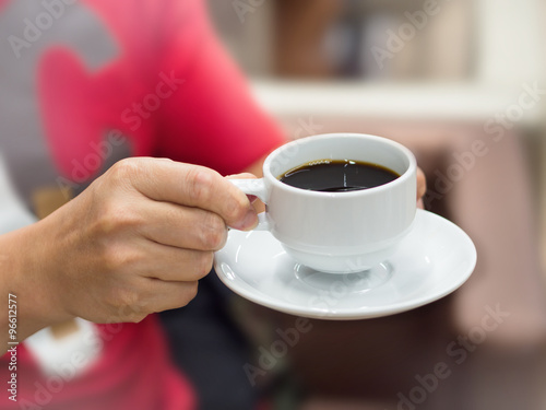 Black coffee in white cup with men hand holding