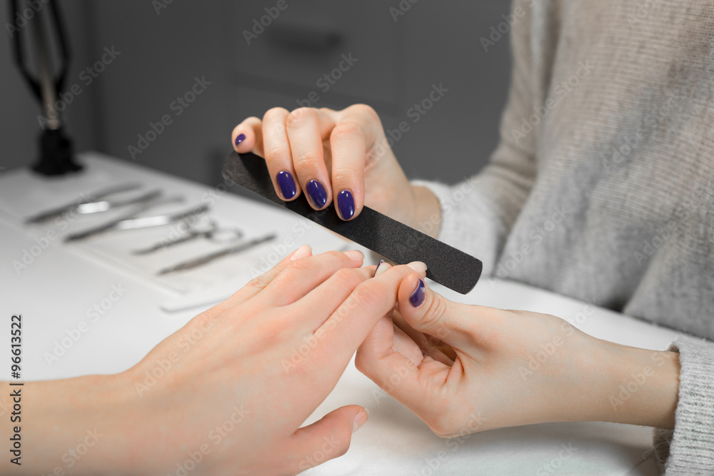 Manicure process with nail file in beauty salon