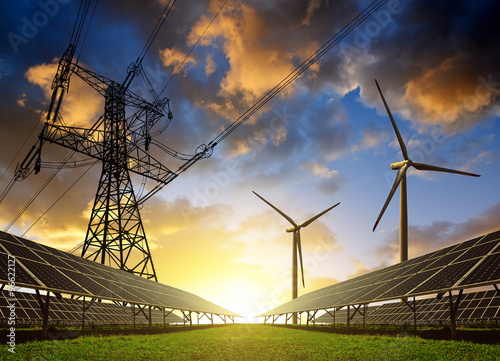 Fotografia, Obraz Solar panels with wind turbines and electricity pylon at sunset