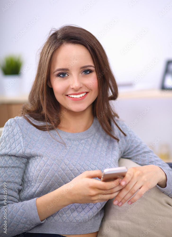 Pretty girl using her smartphone on couch at home in the living room Pretty girl using her smartphone on couch at home in the living room