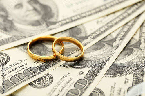 Golden wedding rings on one hundred dollars bill background