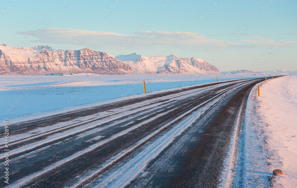 The road on a sunny winter day along  the snow-capped mountains. The Ring Road (Route 1) of Iceland, between Hof and Jokulsarlon. South of Iceland