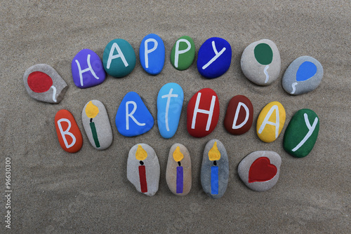 Happy Birthday message on colored stones over the sand