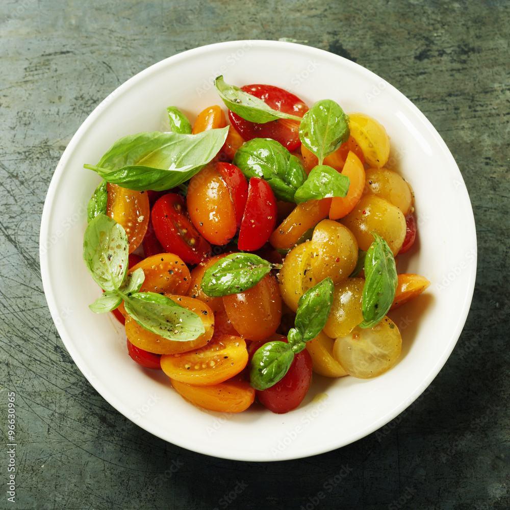 Fresh tomatoes with basil leaves in a bowl
