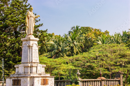Statue of Jesus in Se Cathedral church around palm trees in Panaji, Old Goa, India