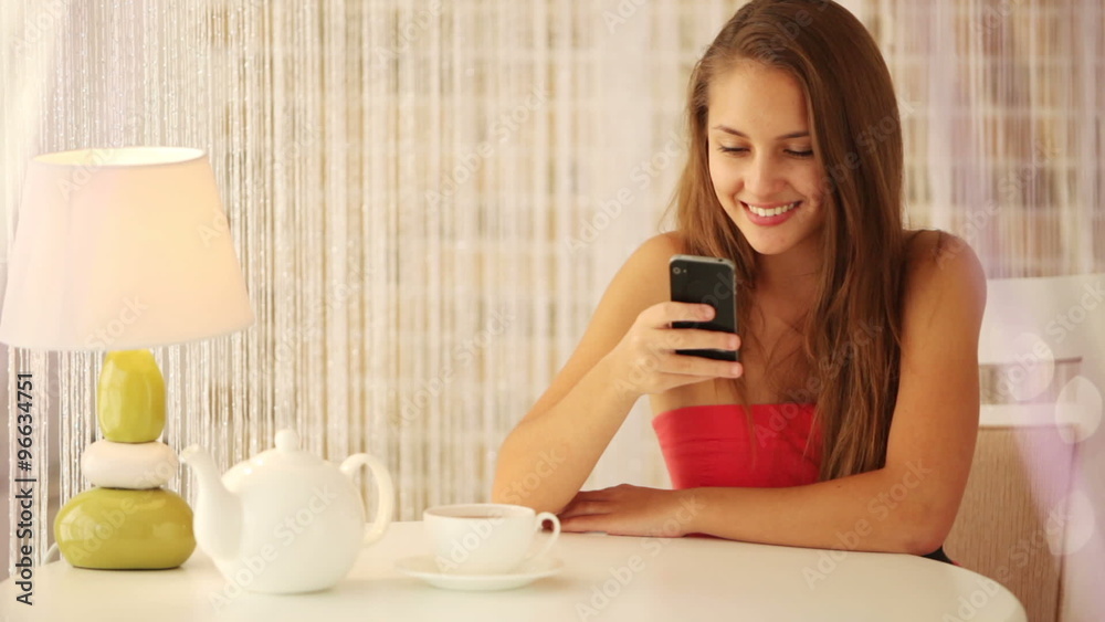 Attractive girl sitting at cafe using cellphone and smiling at camera. Panning camera Attractive girl sitting at cafe using cellphone and smiling at camera. Panning camera