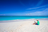 Young man with laptop on white tropical beach