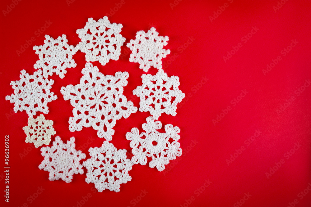 snowflakes crocheted from white thread on a red background