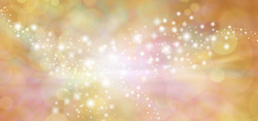 Golden starry glitter warm toned bokeh background banner - Wide autumnal orange and gold  sparkling glittery star speckled background with a whoosh of movement in the middle