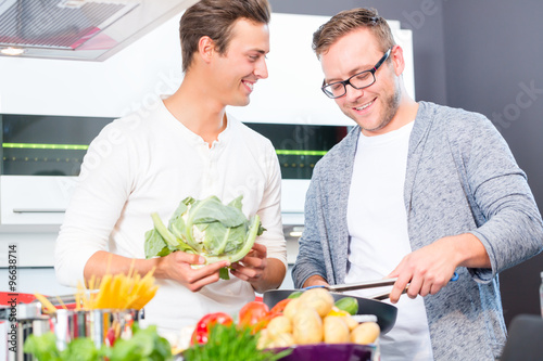 Freunde kochen Gemüse und Fleisch zuhause in Küche