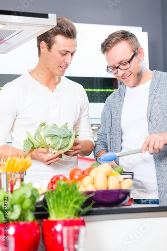 Freunde kochen Gemüse und Fleisch zuhause in Küche