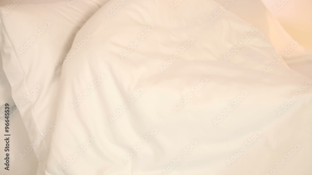 Cheerful girl lying in bed pulling blanket over her head laughing and smiling at camera Cheerful girl lying in bed pulling blanket over her head laughing and smiling at camera