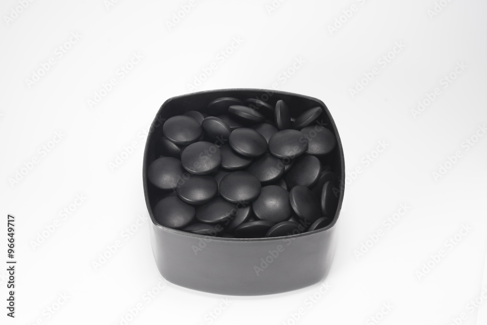 Black  Go stones in a bowl.