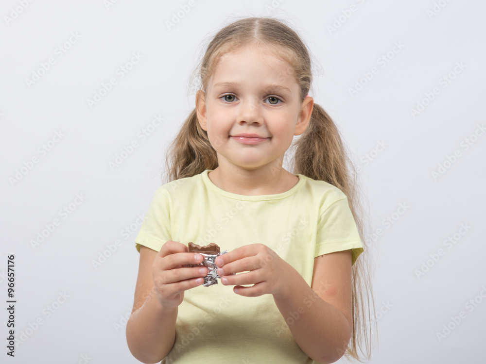 Portrait of a four-year girl sweet tooth with chocolate in hand