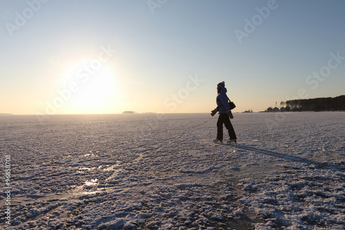 The woman skating on the frozen river in the winter at sunset