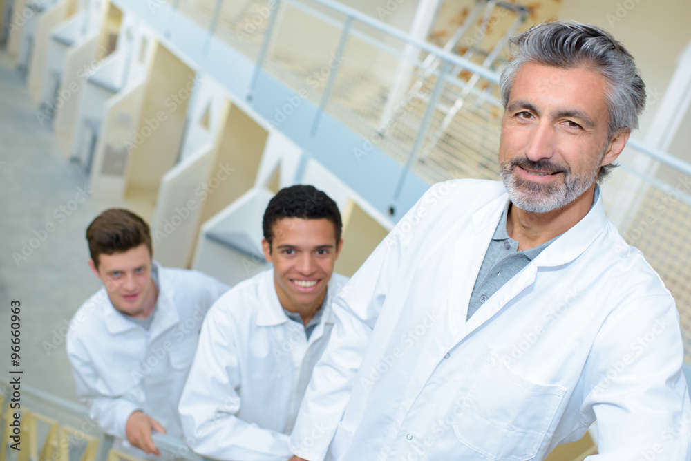 Man with two young men in white jackets Man with two young men in white jackets