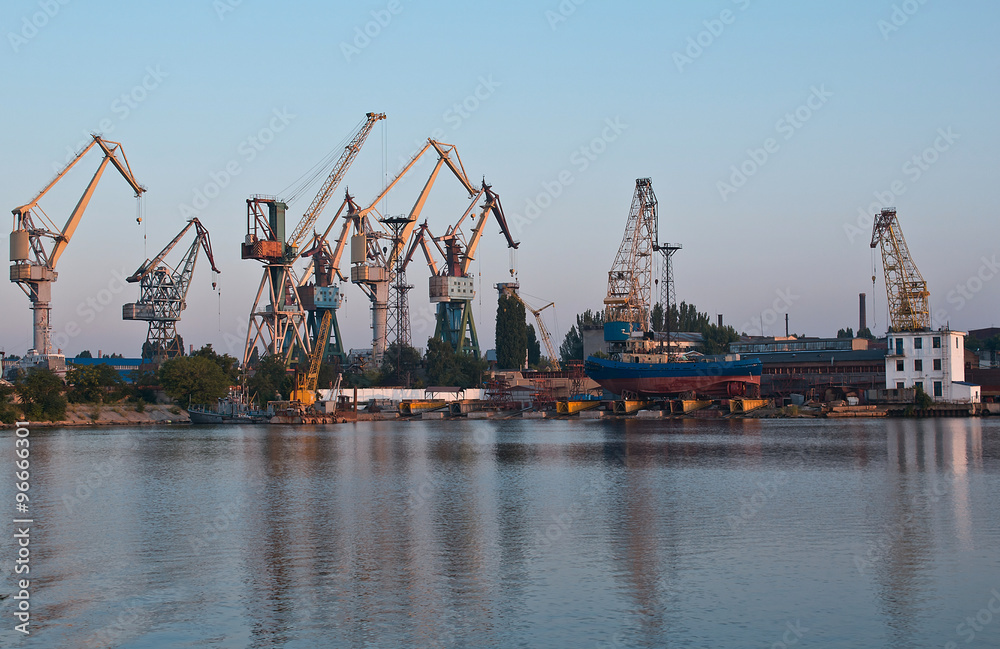 Shipyard with colorful cranes in early morning near loading docks.