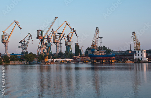Shipyard with colorful cranes in early morning near loading docks.