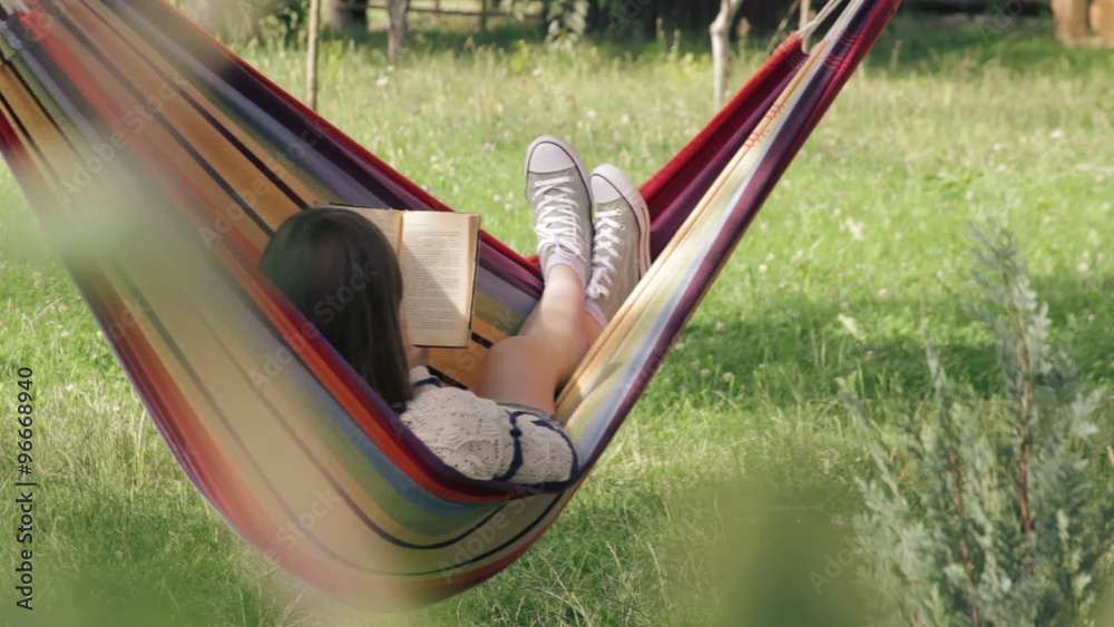 Girl in hammock reading a book - wide shot
