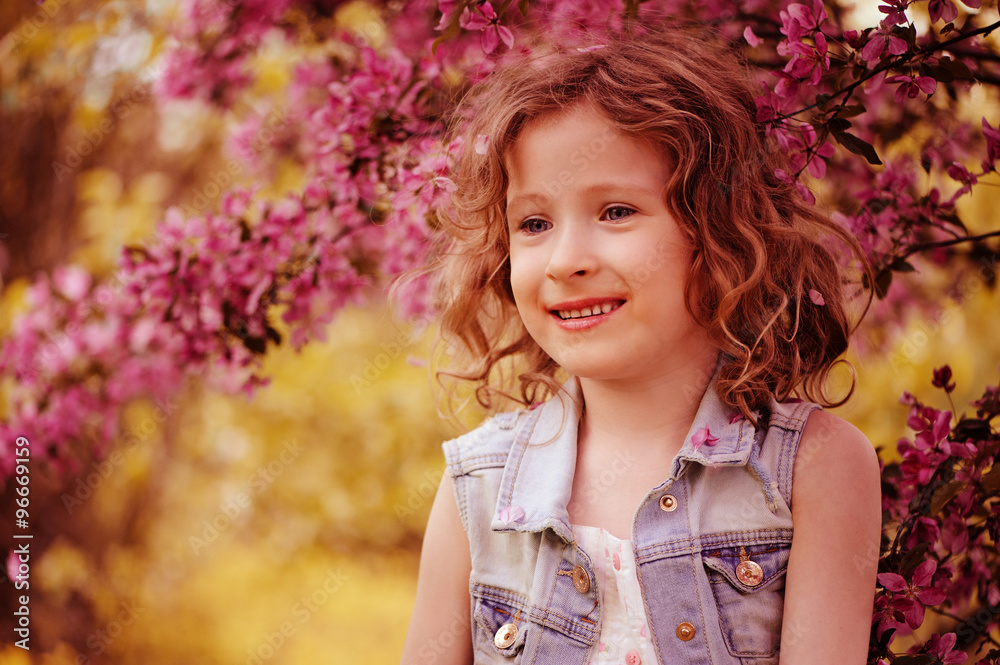happy child girl in pink dress playing outdoor in spring garden near blooming crabapple tree