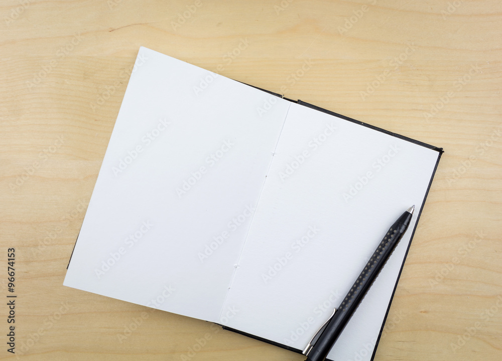 Open notebook with black pen, on wooden surface. Open notebook with black pen, on wooden surface.
