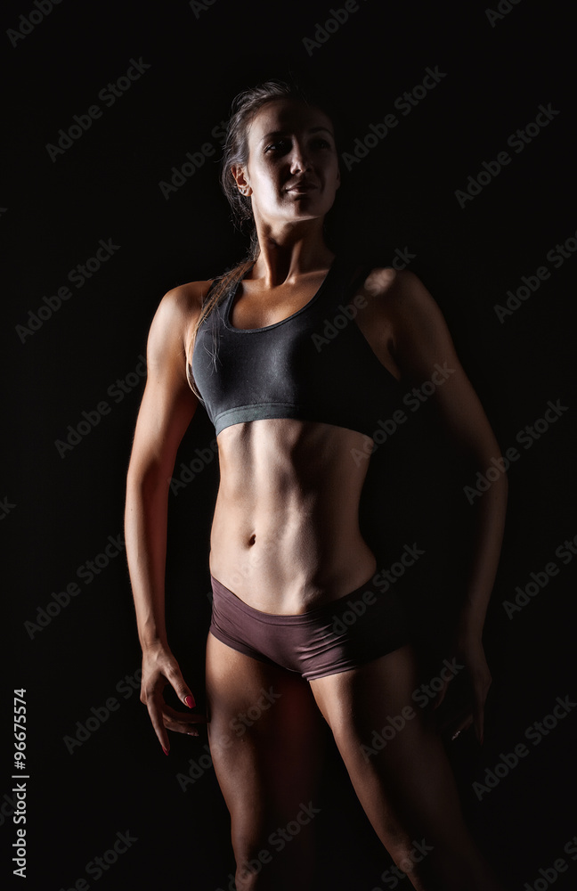 fitness woman in sport style standing against black background