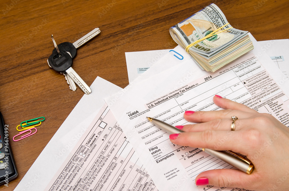 Obraz premium Woman hand filling income tax forms 1040