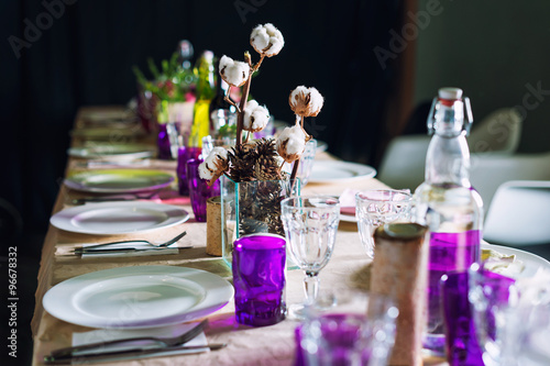 Decorated table ready for dinner. Beautifully decorated table set with flowers, candles, plates and serviettes for wedding or another event in the restaurant.