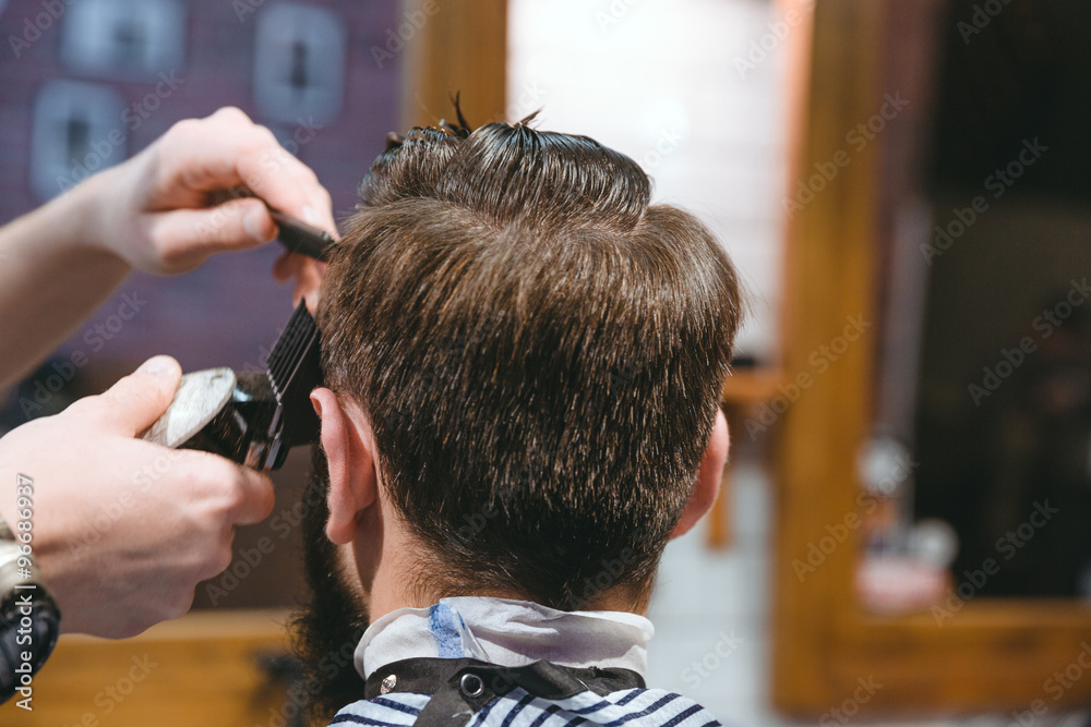 Barbers hands making haircut to man using trimmer