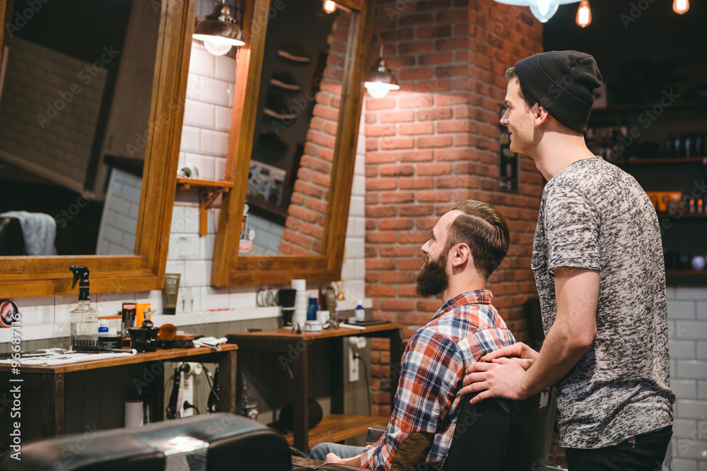 Smiling hairstylist and plesed man client looking in mirror Smiling hairstylist and plesed man client looking in mirror