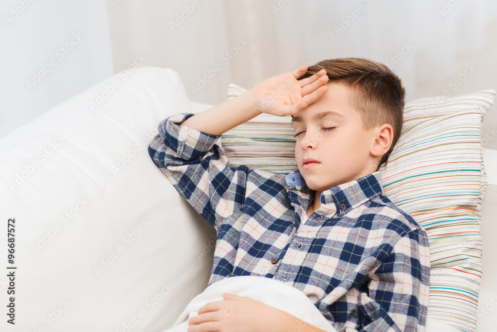 ill boy lying in bed and suffering from headache