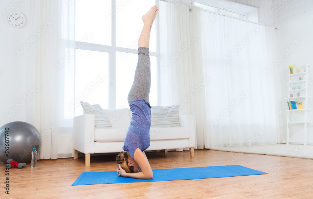 woman making yoga in headstand pose on mat