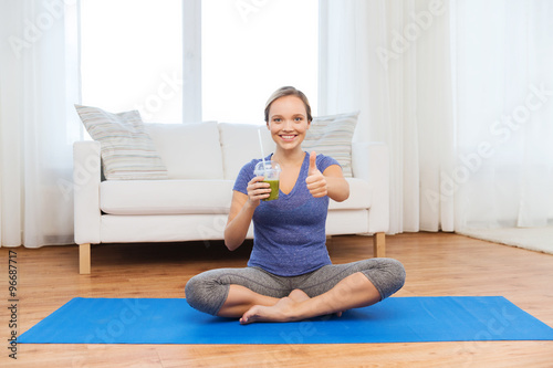 woman with smoothie showing thumbs up at home