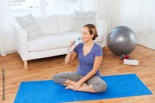 happy woman with water bottle exercising at home