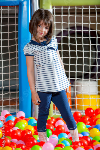 A girl in the playing room with many little colored balls photo