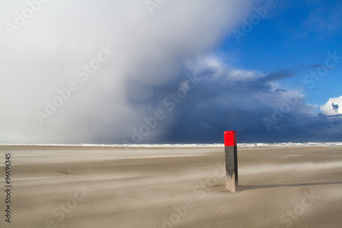 Beach pole in sandstorm, low clouds above the sea. photo