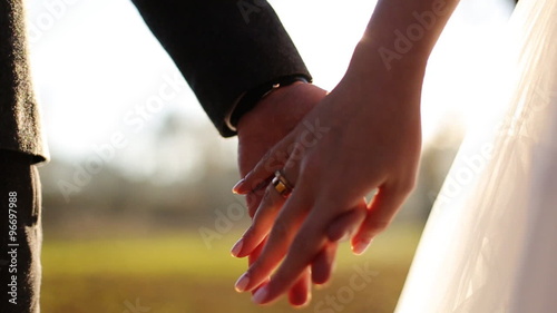 Wedding couple holding hands on sunset background shot in slow motion  close up