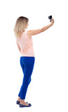 back view of standing young beautiful  woman  and using a mobile