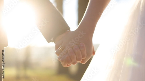   Close up of wedding couple holding hands at sunset 